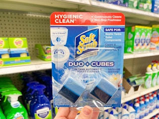 A package of Soft scrub duo cubes held out by hand in front of store shelves with other cleaning products on them.