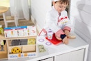 a boy playing with toy food on a melissa & doug sandwich counter