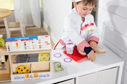 a boy playing with toy food on a melissa & doug sandwich counter