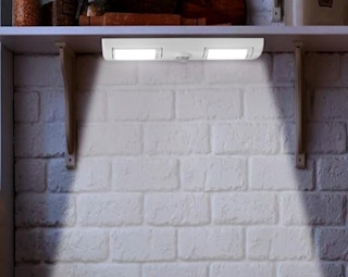 a closet light under a shelf on a wall