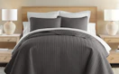 a brown quilt set on a bed