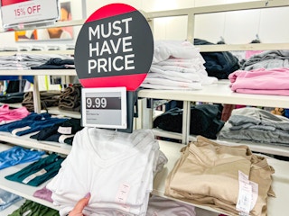 a hand grabbing a tshirt off of a shelf at kohl's