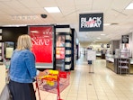 woman pushing a shopping cart inside jcpenney under black friday in july sign
