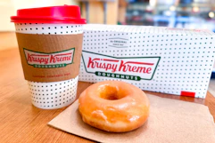A Krispy Kreme donut and small coffee sitting on a table at the store