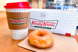 A Krispy Kreme donut and small coffee sitting on a table at the store