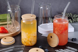 glasses with bamboo lids and straws on a table
