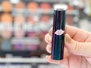 hand holding wet n wild lipstick in front of display