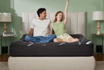 couple sitting on top of mattress topper