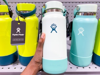 a hydroflask being held in front of a display of other hydrflasks