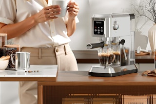 woman enjoying coffee near her espresso machine