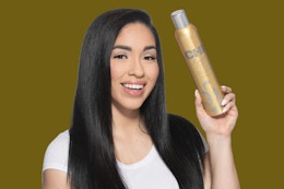 a person holding a gold can of hair sray