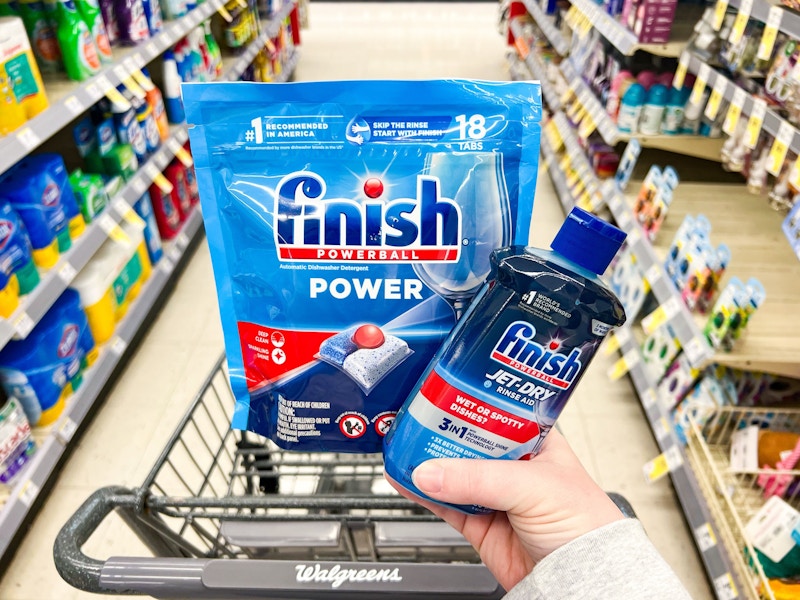 person holding finish dishwasher tabs and rinse aid over a walgreens cart