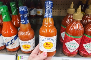 hand holding a bottle of sweet baby rays hot sauce at kroger