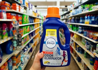 hand holding febreze odor eliminator in aisle at walmart