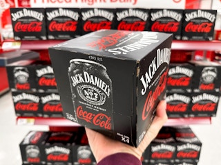 Someone holding a box of Jack Daniels Coca Cola cans in front of a shelf at Target