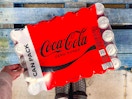 hand touching a pack of coca cola drinks