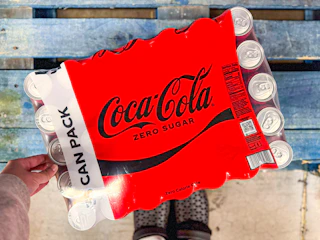 hand touching a pack of coca cola drinks