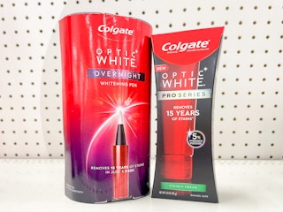 A Colgate Optic White Whitening Pen standing next to a Colgate Optic White toothpaste on a store shelf.