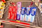 colgate and crest toothpaste with an oral-b toothbrush in a cart