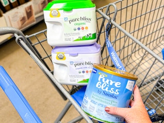 hand holding a similac pure bliss infant formula in walmart cart