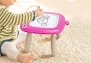 a kid drawing on a pink drawing board table