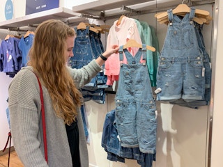 A woman looking for a size large enough to fit her in the kids clothing section.