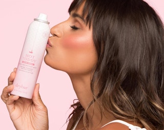 a woman holding a pink can of hairspray