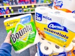 hand holding bounty paper towels alongside charmin toilet paper