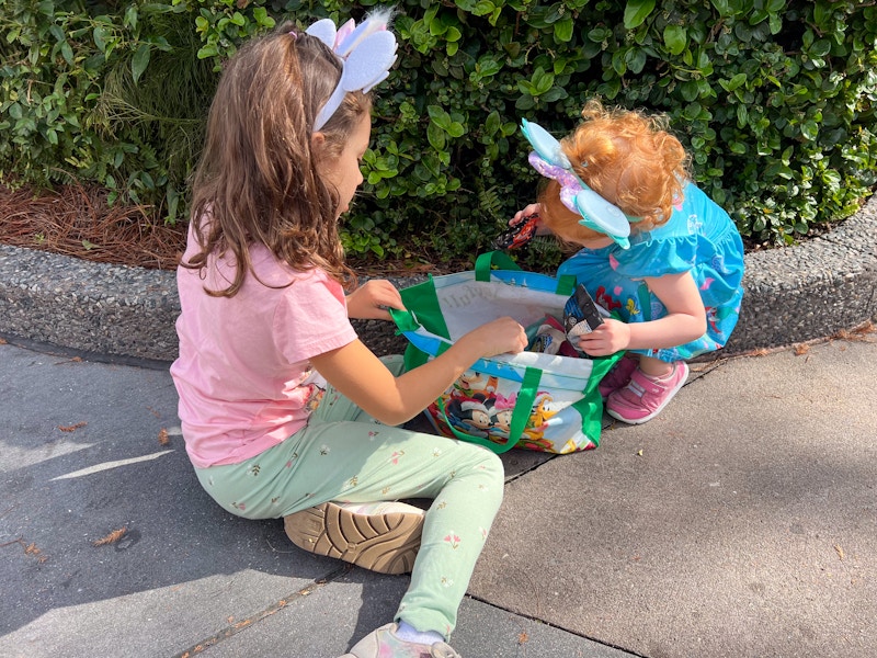 children wearing mouse ears looking at snacks in a bag at disney world