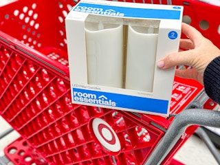 hand holding a room essentials led candle set in front of a target cart