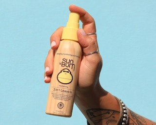 a hand holding a bottle of leave-in conditioner spray