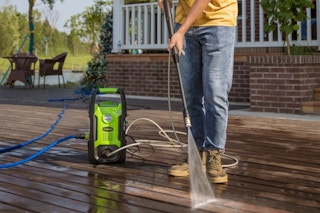 a man using a pressure washer on a deck