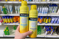 hand holding neutrogena beach defense spray sunscreen