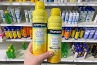 hand holding neutrogena beach defense spray sunscreen