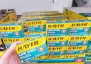hand holding box of Bayer aspirin in front of display