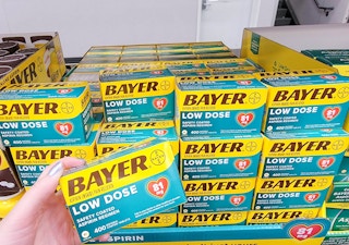 hand holding box of Bayer aspirin in front of display