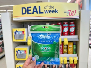 hand holding pack of Oral-B Glide Floss pick in front of display