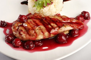 A plate of grilled chicken with cherry sauce