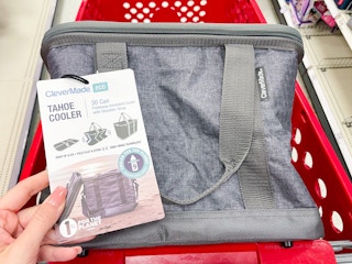A CleverMade cooler sitting in a store shopping cart. The tag on the cooler is held out by hand.