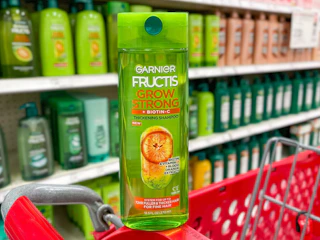 A Garnier Fructis Grow Strong shampoo sitting on the edge of a store shopping cart.