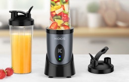 a blender full of fruit next to a cup with fruit juice 