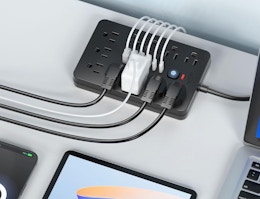 a flat surge protector with plugs next to a laptop and tablet