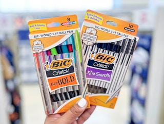 hand holding two boxes of BIC Cristal pens in aisle