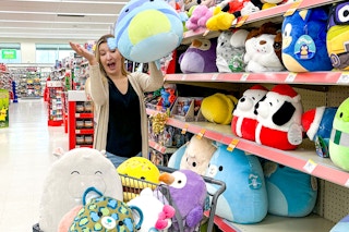 a person tossing a squishmallow into a cart at walgreens