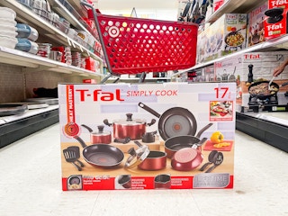 A box of T-fal simply cook cookware sitting on the ground in the middle of a store aisle with a Target shopping cart in the background.