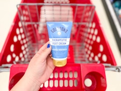 hand holding a tube of hold bond foot cream in front of a target cart