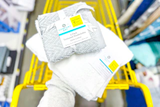 hand holding comfort bay towels above yellow shopping cart