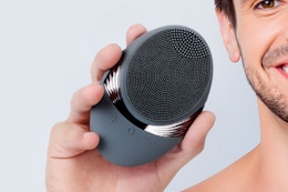 Man holding the COSLUS Facial Cleansing Brush Face Scrubber in hand.