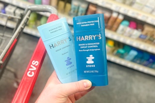 person holding 2 harrys deodorants by a cvs cart