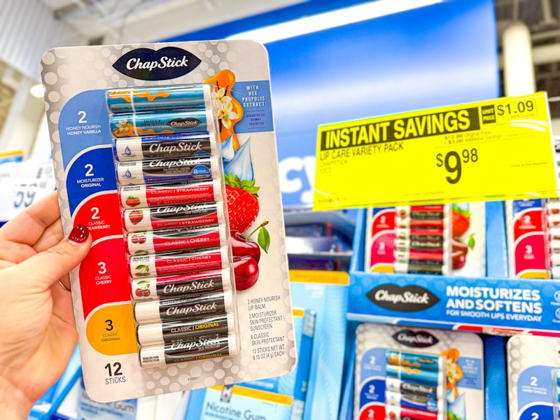 person holding a chapstick variety pack by a sale sign for $9.98